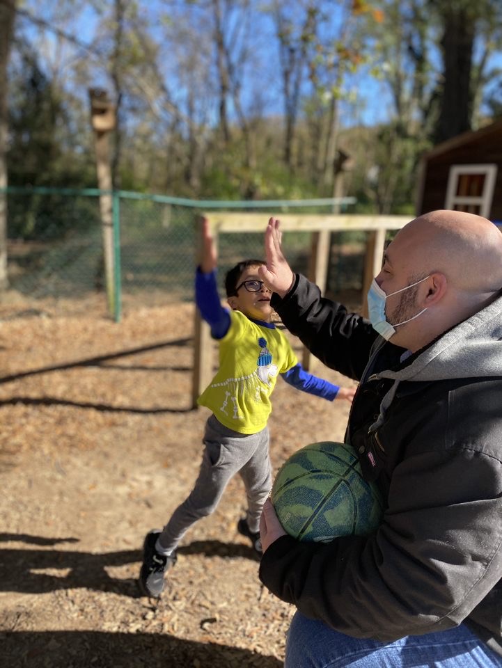 Male ECE Teacher providing young child high five.